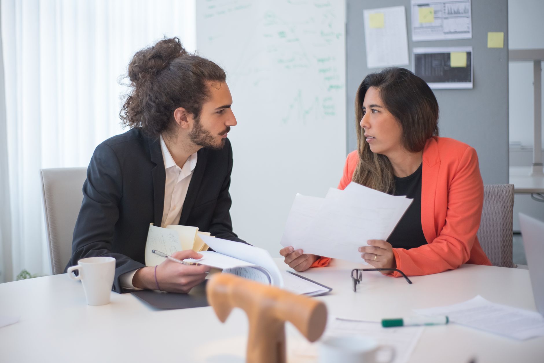 Dos profesionales revisando documentos en una reunión de trabajo